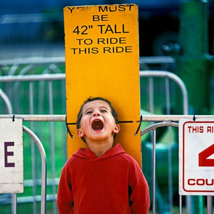 An amusement ride sign saying you must be this tall to ride